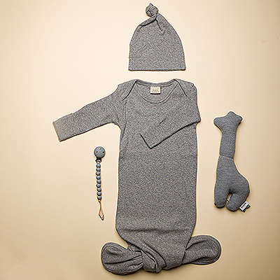 Bienvenue au nouveau bébé avec cet ensemble-cadeau Mushie! Il comprend une barboteuse en coton biologique avec des boutons et un bonnet assorti, un porte-tétine en silicone et un charmant hochet girafe en coton biologique de Trixie.